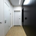 Czarny stojący mebel w pustym, jasnym przedpokoju z białymi drzwiami