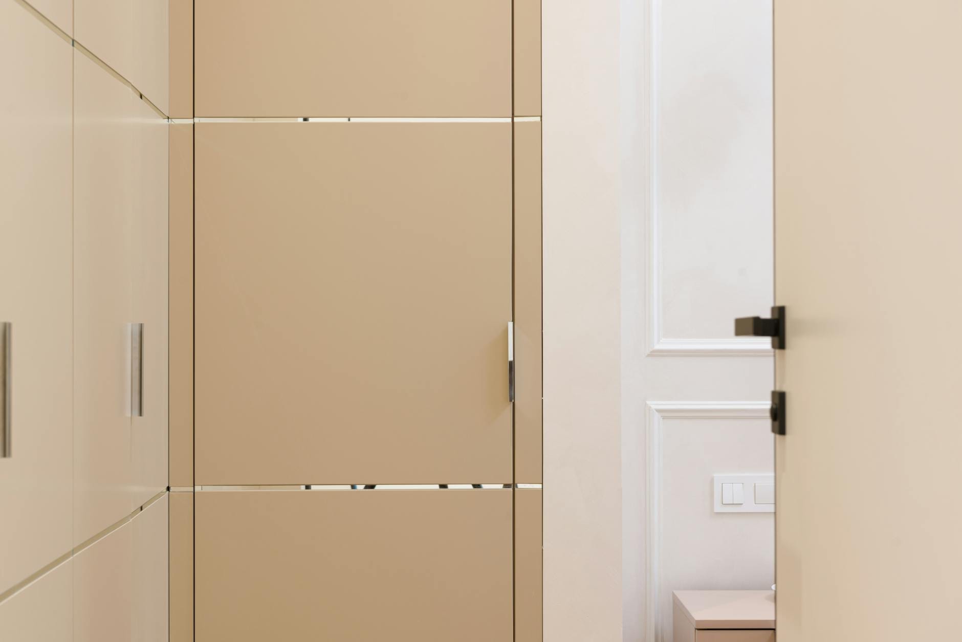 Jasny, minimalistyczny korytarz z zabudowanymi szafami i gładkimi drzwiami