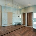 Nowoczesny przedpokój z dużym lustrem i drewnianą zabudową