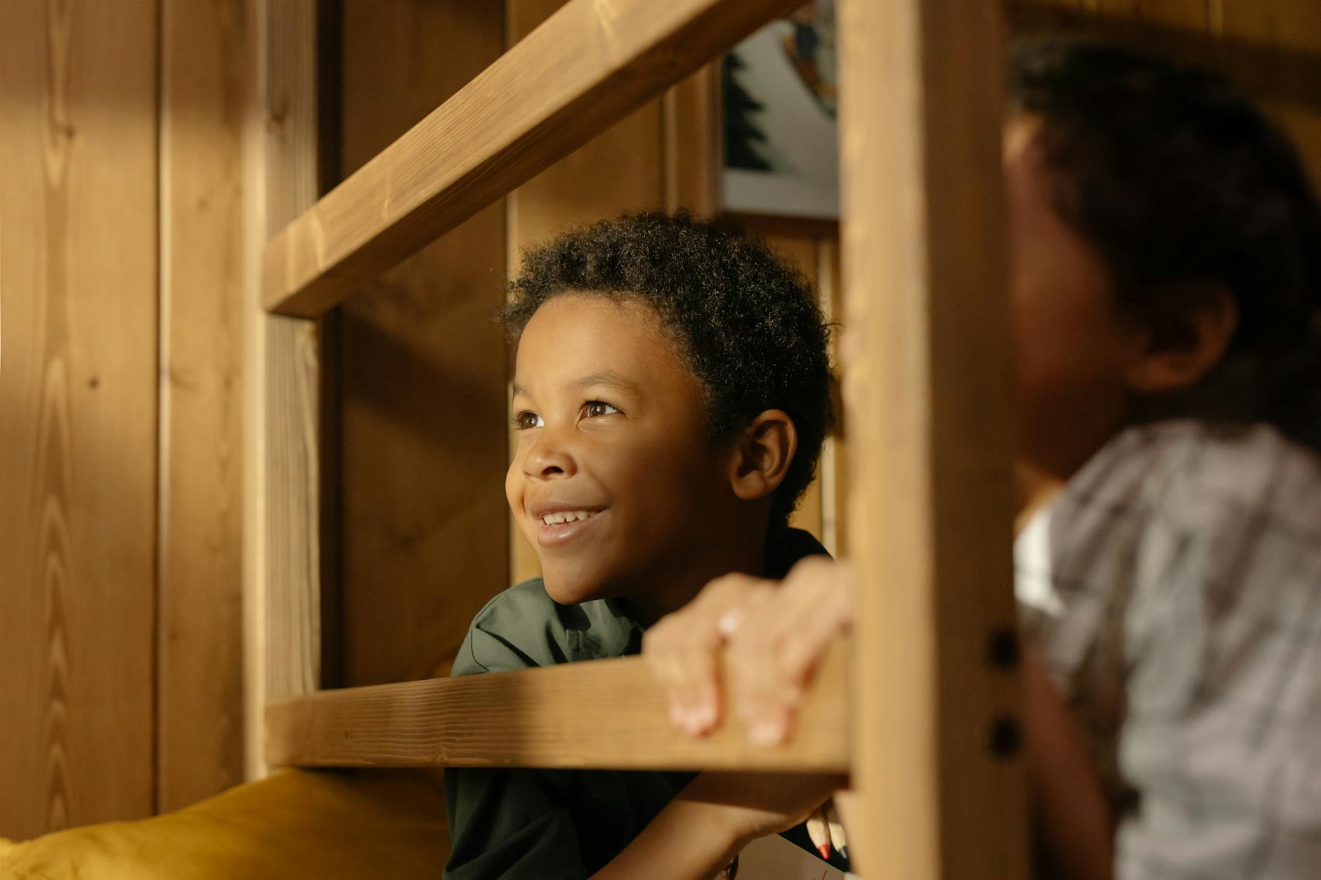 Dwoje dzieci bawi się na drewnianym łóżku piętrowym w słonecznym pokoju