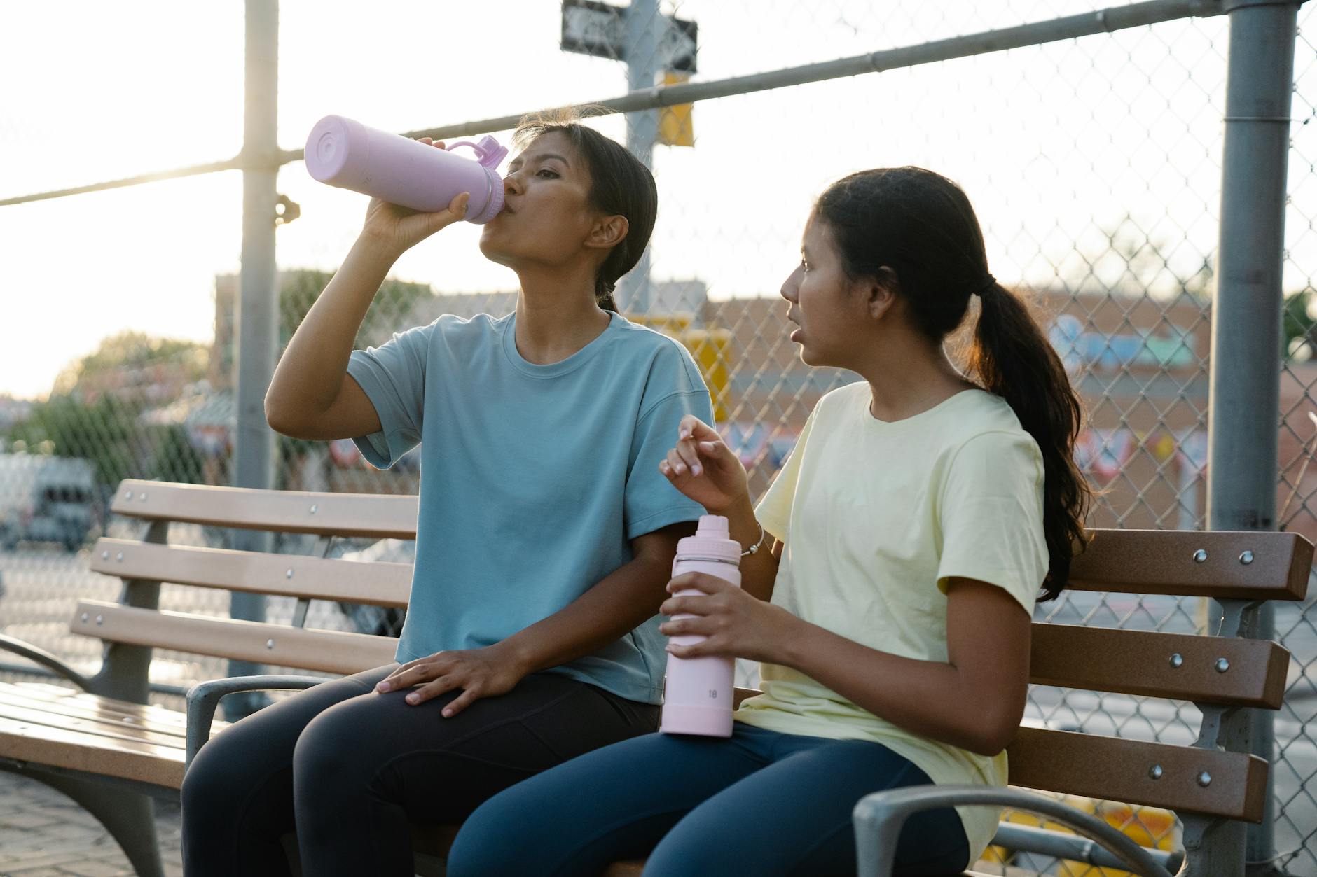 Mama z córką piją napoje na ławce podczas słonecznego spaceru