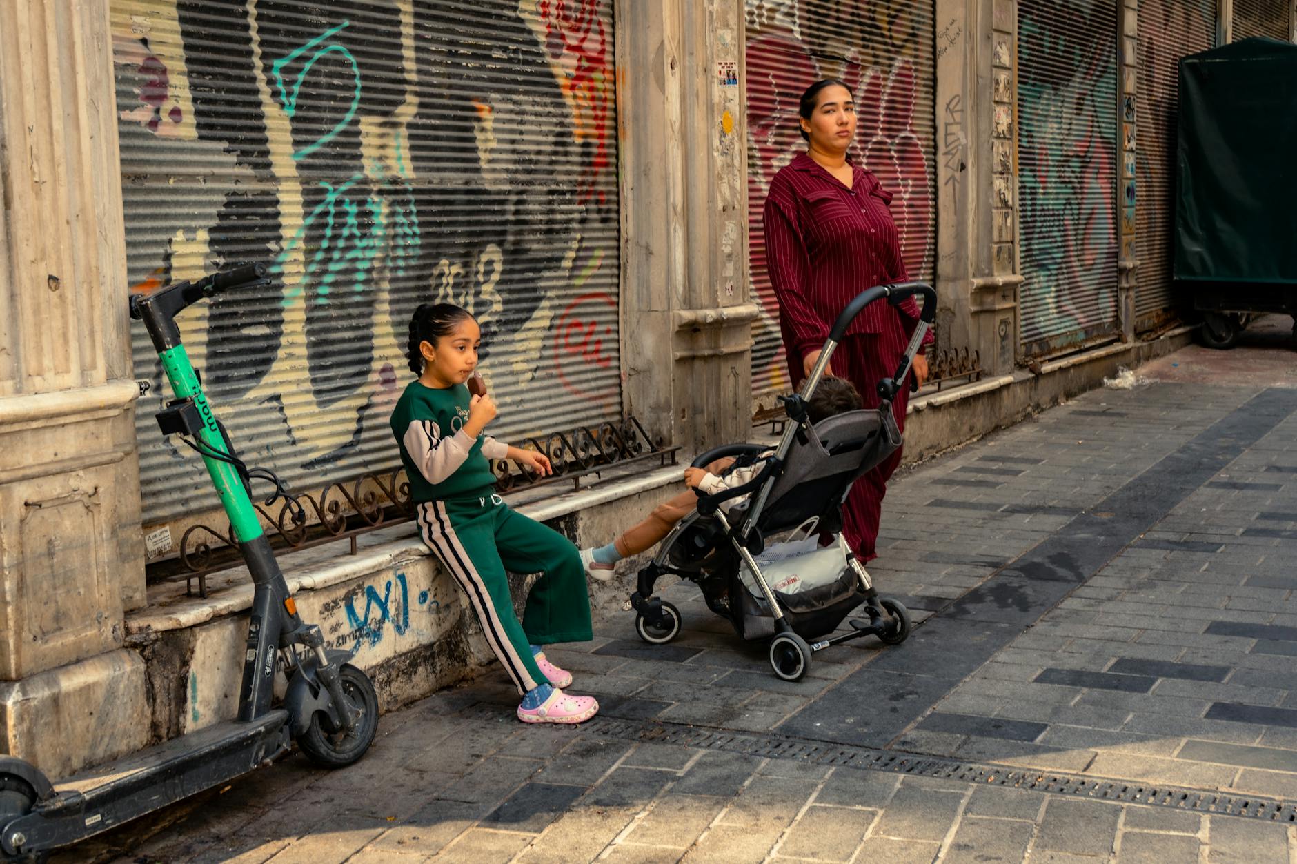 Mama z dziećmi je lody na kolorowej, miejskiej ulicy z graffiti