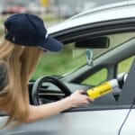 Policjantka sprawdza trzeźwość kierowcy alkomatem na drodze