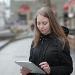 Młoda kobieta korzysta z tabletu w miejskiej przestrzeni Wi-Fi