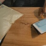 Osoba zarządza logistyką zwrotów na tablecie obok paczki na biurku