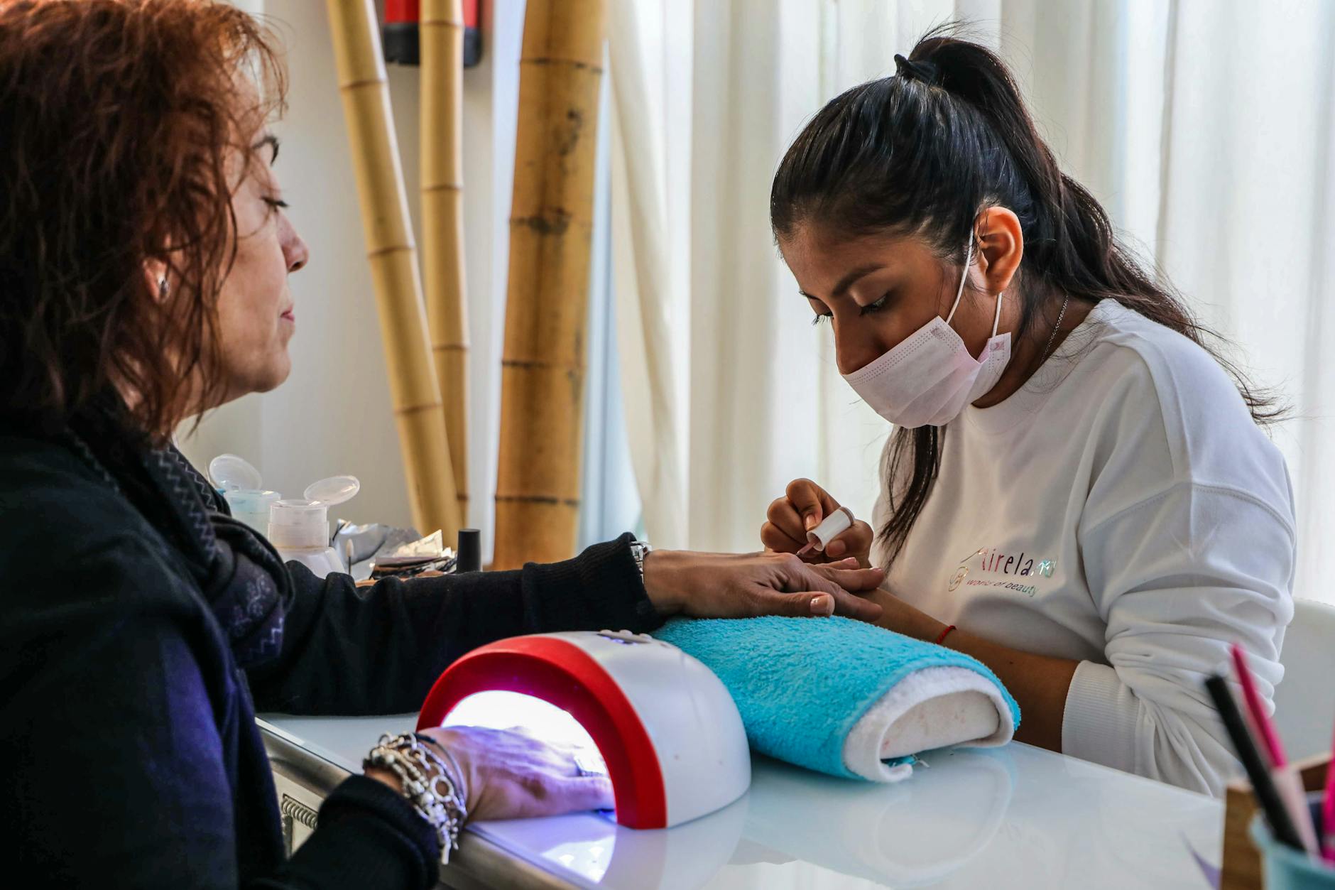 Stylistka wykonuje delikatny manicure paznokci w salonie
