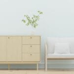 Minimalistyczny salon z drewnianą komodą, fotelem i roślinami
