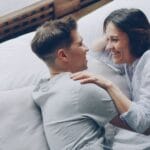 Para śmiejąca się i przytulająca na łóżku w sypialni