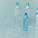Puste plastikowe butelki na przezroczystej półce na niebieskim tle