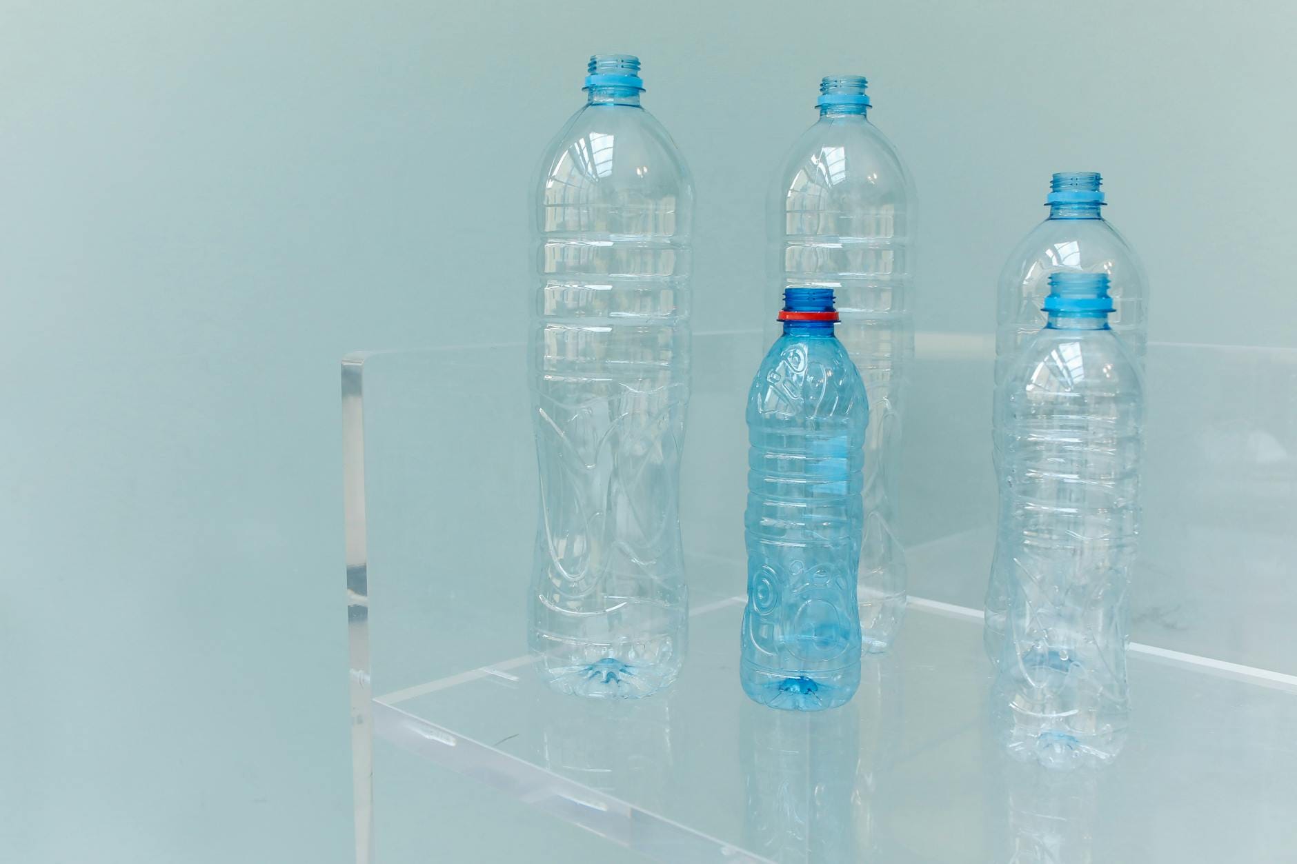 Puste plastikowe butelki na przezroczystej półce na niebieskim tle